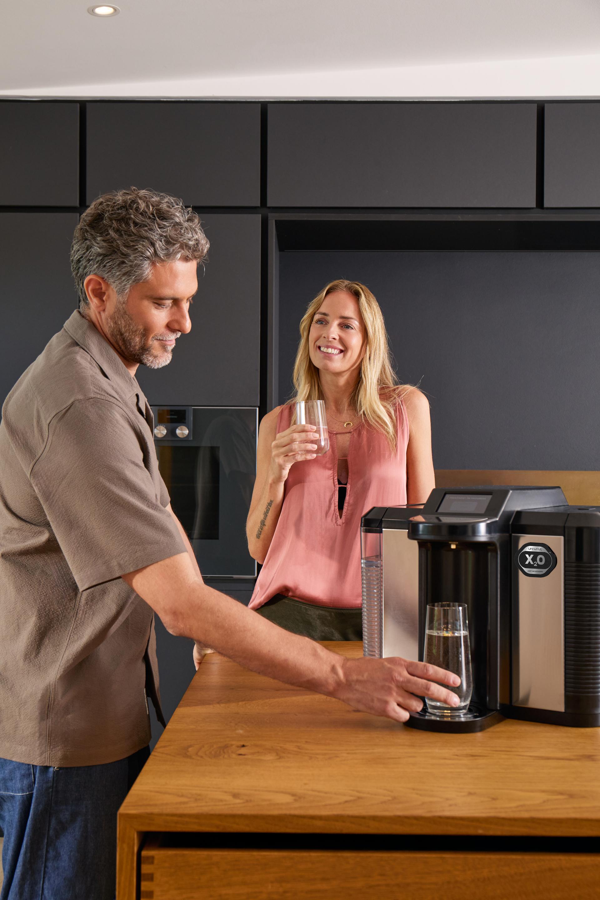 Couple enjoying X2O water together in their kitchen
